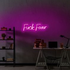 a purple neon sign that reads create on the wall next to a desk and chair