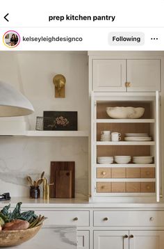 a kitchen with white cupboards and wooden shelves filled with dishes on top of them