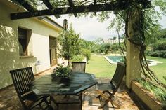 an outdoor dining area with table, chairs and pool in the backgroung