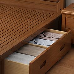 a wooden bed with drawers underneath it on top of a hard wood floored floor