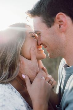 a man kissing a woman's face with the sun shining through her hair and nose