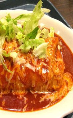 a white plate topped with meat covered in sauce and garnished with lettuce