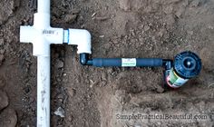 a pipe laying in the dirt next to a white pole with a spigot on it