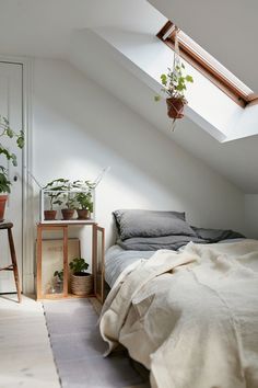 a bed sitting under a skylight in a bedroom next to a wooden table and chair