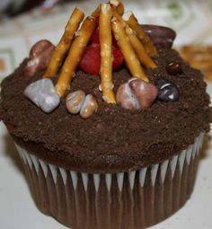 a cupcake with chocolate frosting topped with strawberries and candy sticks on top