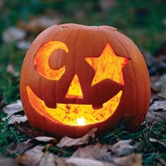 a carved pumpkin sitting on the ground with its eyes open and glowing in the dark