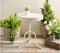 a white table topped with potted plants on top of a wooden floor