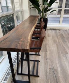 a long wooden table sitting in front of a window next to a potted plant