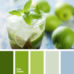 a glass filled with ice and mint on top of a table next to green apples