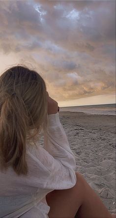 a woman sitting on top of a sandy beach