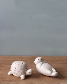 two white ceramic turtle figurines sitting on top of a wooden table