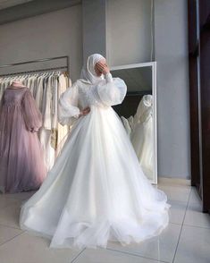 a woman standing in front of a closet full of wedding gowns and dresses on hangers