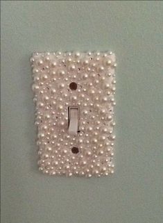 a single light switch cover with pearls on the front and back of it, hanging from a wall