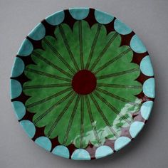 a green and brown plate with blue dots on the rim, sitting on a gray surface