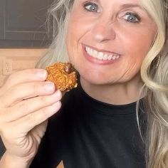 a woman is smiling while holding a piece of food