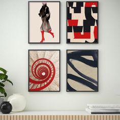 four framed art pieces on the wall above a table with a vase and plant in it