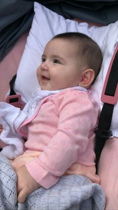 a baby sitting on top of a bed next to pillows