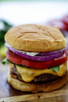 a cheeseburger with onions, tomato and lettuce