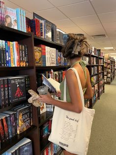 a woman standing in front of a bookshelf with a bag on her shoulder