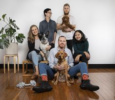 a group of people sitting next to each other on a wooden floor with a dog