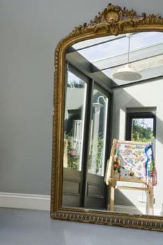 a mirror sitting on top of a white floor next to a wall with a painting in it