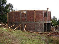 an unfinished building with wooden beams on the roof and windows in the middle of it