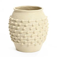 a white ceramic vase with pom - poms on the outside and inside it