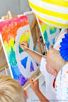 a little boy painting on an easel with his hands