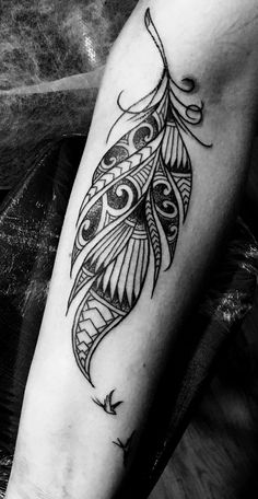 a black and white photo of a feather tattoo