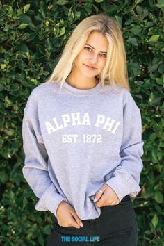 a woman standing in front of some bushes wearing a sweatshirt that says, aloha phi est 1932