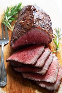 sliced steak on cutting board with knife and fork