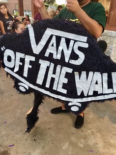 a man holding up a sign that says vans off the wall