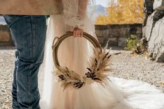 a man and woman standing next to each other holding a basket with feathers on it