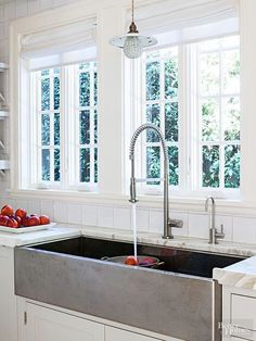 a kitchen sink sitting under a window next to a counter top with fruit on it