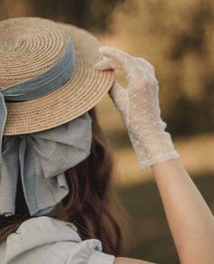 a woman wearing a hat and gloves with her hand on the top of her head