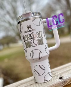 a tumbler cup with baseball mom on it sitting on a wooden table outside in the sun