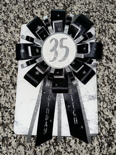 a black and white ribbon with the number twenty five on it is laying on a marble surface