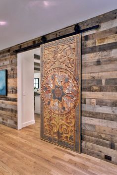 a room with wood paneled walls and a large wooden door on the wall is decorated with intricate designs