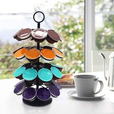 a stack of colorful plates sitting on top of a table next to a cup and saucer