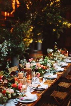 a long table is set with plates and candles for an outdoor dinner party in the evening