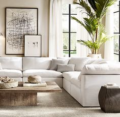 a living room with white furniture and large windows