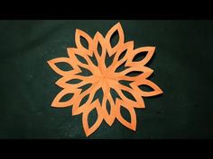 an orange paper flower on a green surface