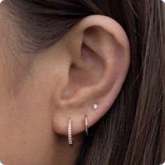 a woman's ear is shown with two small diamond hoops on the side