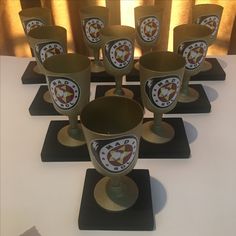 there are many cups on the table with their name and emblem painted on each cup