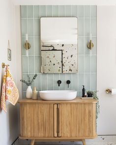 a bathroom sink sitting on top of a wooden cabinet next to a wall mounted mirror