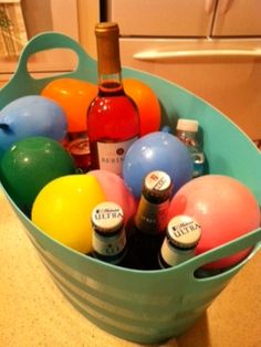 a bucket filled with lots of different types of balls and bottles in front of a refrigerator