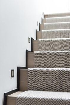 the carpeted stairs are lined with black and white herringbones on each side