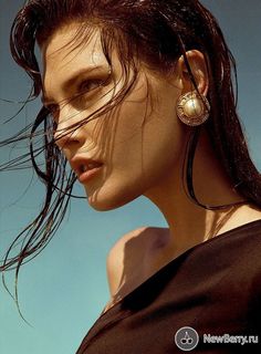 a woman with her hair blowing in the wind and wearing large earrings on top of her head