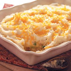 a casserole dish with mashed potatoes and cheese in it on a table