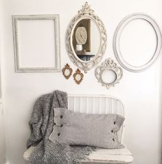 a white bench sitting under a mirror next to two framed pictures and other items on the wall